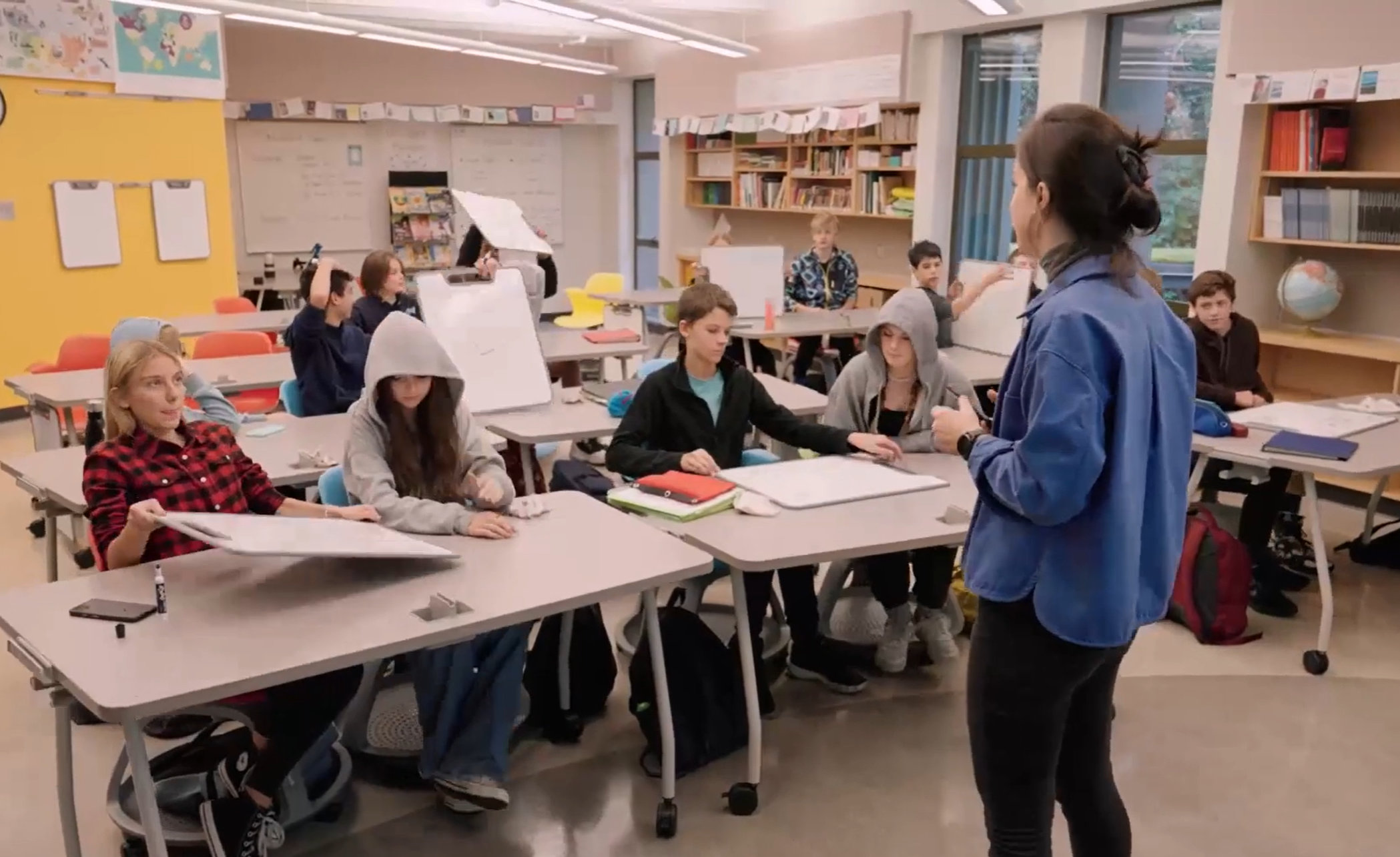 Teacher standing in front of engaged students sitting behind a desk 